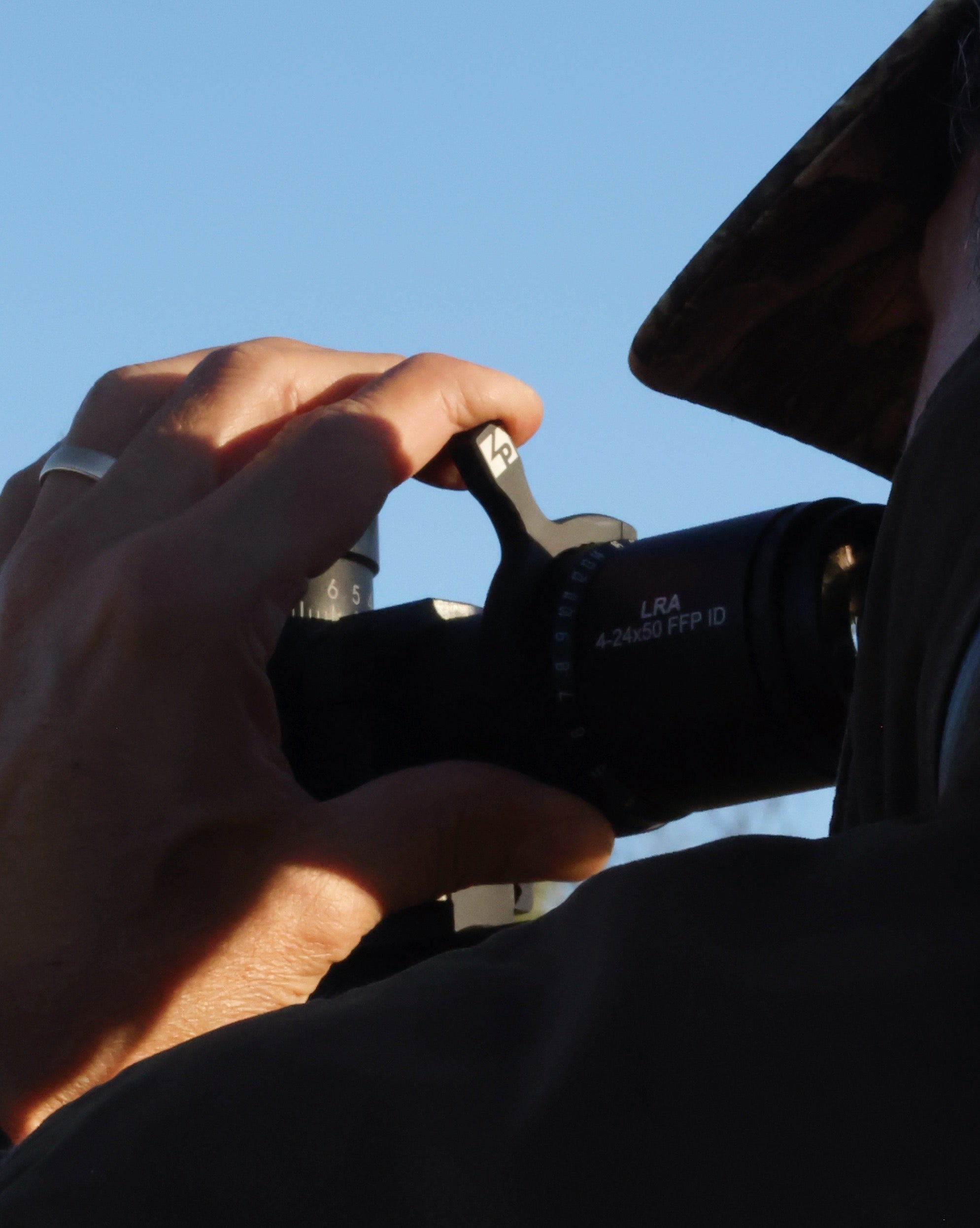 Hunter adjusting the throw lever on a Legend rifle scope during a hunting trip, ensuring accuracy in the field